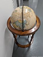 Globe showing Asia and Australia regions on wooden stand, viewed from an angled perspective.