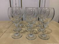 Nine clear wine glasses arranged on a table, standing upright showing their classic shape and polished finish.