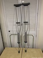 Pair of full-length used aluminum Guardian crutches, adjustable up to 50 inches, with rubber grips and foot tips.