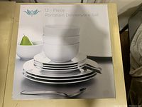 Photo of the boxed 12 piece porcelain dinnerware set showing stacked bowls and plates.