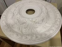 Top view showing ornate embossed leaf and scroll design with central hole