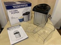 Photo showing Toastess hot air corn popper, original box, instruction booklet, and detachable plastic chute and cover.
