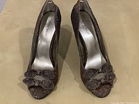 Top down view of pair of glitter Nine West women's high heel shoes, showing peep toe and decorative bows on front.