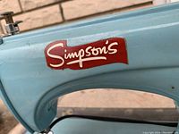 Close up photo of the light blue sewing machine with the red and white 'Simpson's' logo on the arm.