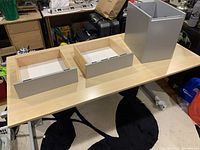 Table top with three wooden drawers and metal frame drawer base unassembled on the floor