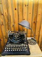 Typewriter and lamp side by side on wooden table against wood-paneled background