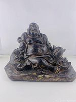 Front view of reclining Buddha statue showing smiling face, exposed belly, and flowing robes