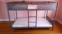 Front view of assembled metal bunk bed frame with two mattresses and central ladder