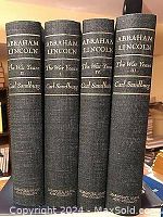 Four volumes of 'Abraham Lincoln The War Years' by Carl Sandburg lined vertically, showing spines with titles and author name in gold lettering on black hardcover binding.