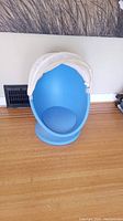 Front view of blue kids egg chair with white removable fabric canopy on a wooden floor.