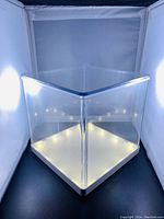 Front view of the large clear plexiglass display cube illuminated with LED lights along the base.