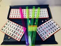 Complete Mahjong set in carrying case showing tiles, sticks, dice, and reference cards.