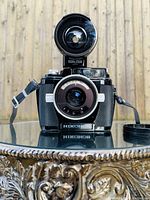 Front view of Nikon Nikonos underwater camera with Sea & Sea flash mounted on top, showing lens and strap.