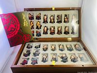 The open wooden box displaying the complete set of the character chess pieces arranged in molded trays along with a red booklet.