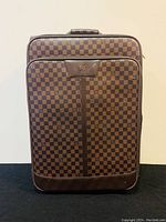 Front view of the brown checkered Louis Vuitton rolling suitcase showing the main zipper compartment and leather logo patch.