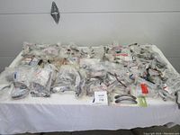 Box of assorted new Richelieu and Amrock cabinet hardware handles, all individually packaged, displayed on table.