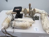 Overview of lot showing 8 inch swivel seat pedestal, 15 lb anchor with chain, five white boat fenders with wear.