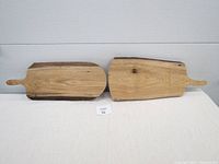 Photo of two butternut wood charcuterie boards side by side on a white surface showing natural wood grain and rustic appearance for lot overview.