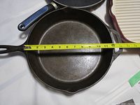 Close-up of 11-inch Lodge cast iron frying pan with measuring tape across inside diameter