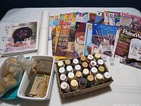 Multiple tole painting books and magazines, binder, acrylic paints, sanding blocks, sponges and tracing paper on a table.