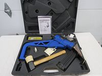 Blue Campbell Hausfeld air flooring nailer with attached magazine, wooden mallet with rubber head, bottle of oil, strips of nails, and instruction sheet arranged inside black plastic carrying case.