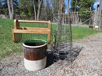 Photo showing entire lot: wooden garden basket, three metal tomato cages, and stoneware crock outdoors on gravel