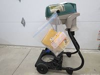 Mosquito Magnet unit assembled on wheeled base with power cord wrapped on base and instruction manual in plastic bag hanging on unit