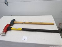 Full view of both Mastercraft 8 lb tools: a splitting maul with red metal head and wooden handle, and a sledge hammer with blue head and yellow/black fiberglass handle.