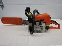 Side profile of Stihl Model 025 chainsaw with guide bar and attached plastic bar cover