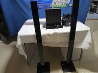 Two tall tower speakers on rectangular bases placed on a table.