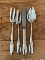 Close-up photo showing individual fork, knife, and spoon pieces with Art Deco style engraved handles.