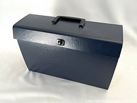 Full view of the dark blue hardboard accordion file folder in closed position with handle on top and toggle closure on front.