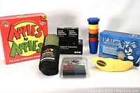 Full lot photo showing Apples to Apples Party Box, Bananagrams pouch open with letter tiles, two decks of Cards Against Humanity, Killer Bunnies box, stacking cups in multiple colors, and poker chips in plastic case.