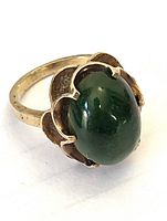 Close-up image of the jade oval cabochon set in 10K gold band with floral prongs.