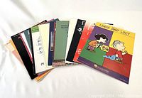 Photo showing 12 piano solo sheet music books fanned out, featuring Linus and Lucy cover in front