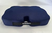 Front view of dark blue Kabooti seat cushion with wedge shape and center cutout showing branded strap.