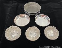 Six small silver-plated serving dishes on black fabric background showing variety of sizes and liners.