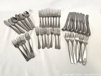 Full set showing knives, forks, dessert forks, and spoons arranged on a white background.
