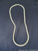 Full view of flexible rope chain necklace laid on black background