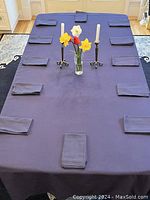 Full view of navy blue cotton tablecloth laid out on a dining table with 12 matching napkins placed on edges.
