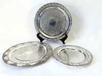 Three silver-plate serving trays displayed together, showing size differences and design details.