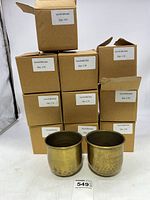 Ten boxed new brass planters stacked with two unboxed in front showing size and finish.