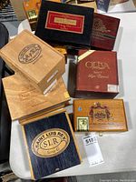 Overview of 9 assorted cigar boxes in various wood finishes and colors displayed on a white surface.