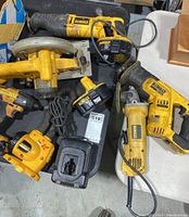 Overhead view of all tools on table: reciprocating saw, circular saw, angle grinder, impact driver, charger, hoses and batteries.