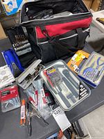 Wide view of various tools laid out with the soft tool bag in the background, including drill bits, clamps, and tool kit
