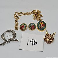 Photo showing all four pieces together: a micro mosaic necklace and clip earrings with floral pattern, a silver-tone marcasite pin, and a gold-tone rhinestone cat pin.