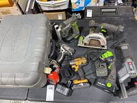 Top view of assortment including Kawasaki circular saw, reciprocating saw, Bostitch nail gun, cordless drill, batteries and charger, and Kawasaki tool case.