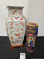 Front view of large hexagonal ceramic butterfly vase and tall cylindrical decorative container with Asian designs placed next to each other