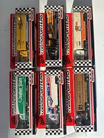 Front view of six Matchbox Star Transporters trucks in original packaging with checkered border and colorful trailers