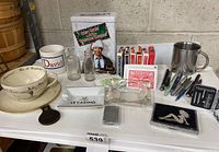 Full view of lot showing mugs, ashtrays, bottles, playing cards, pens, lighter, and Christmas Vacation DVD